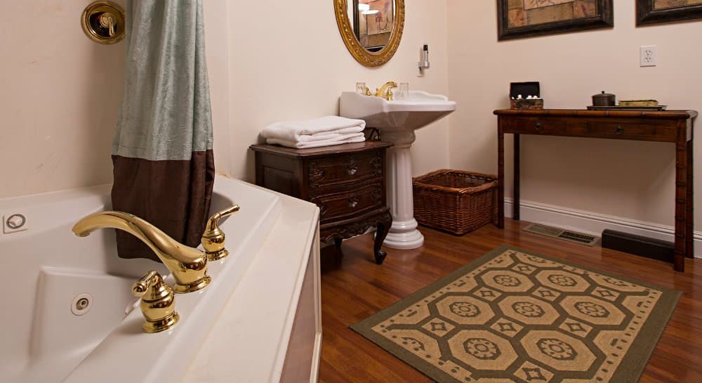 Elegant bathroom featuring a bathtub, sink, and wooden furnishings on a wooden floor.