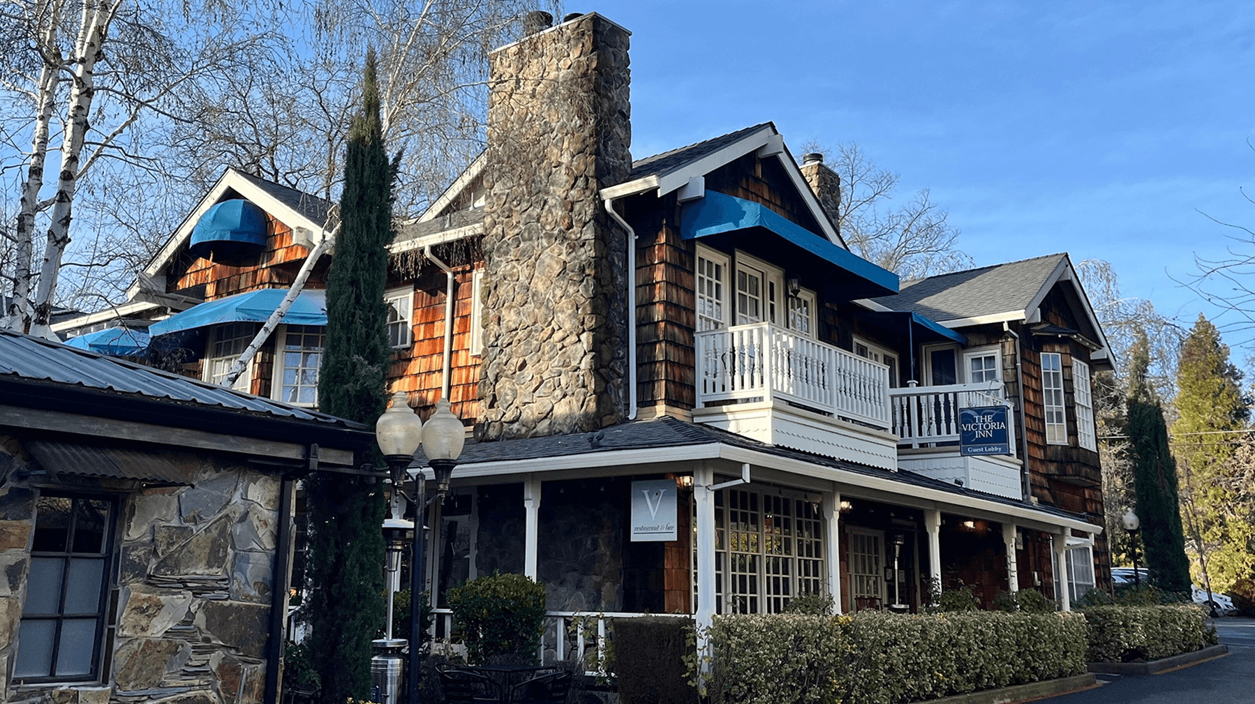 A picturesque stone and wood building with blue accents surrounded by trees.