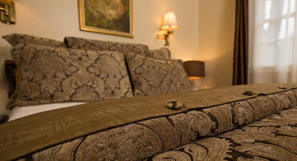 A beautifully arranged bed with ornate pillows and a decorative blanket in a cozy, softly lit room.