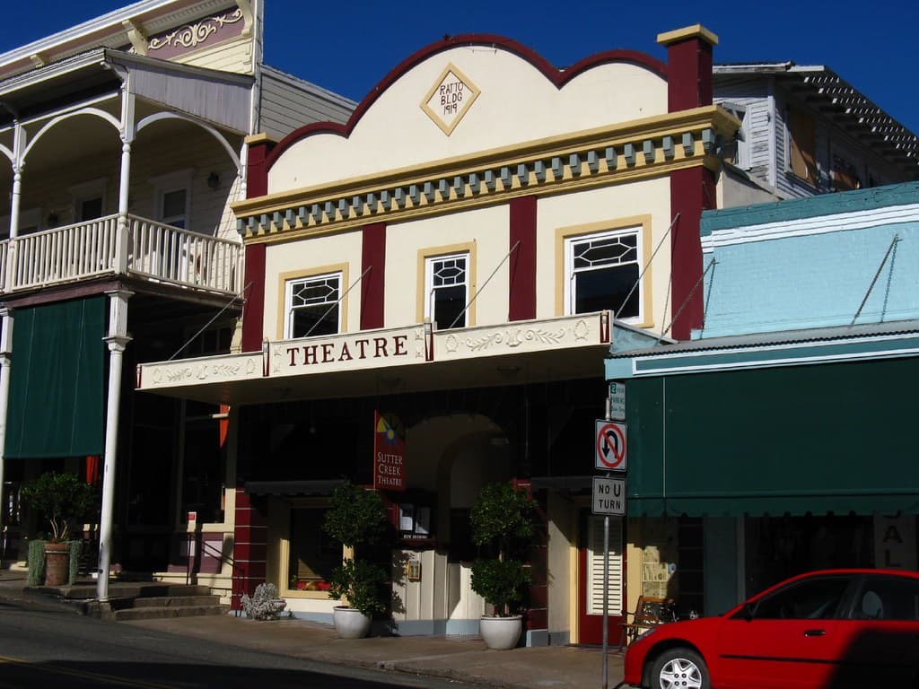 Historic theatre building with decorative facade and potted plants.