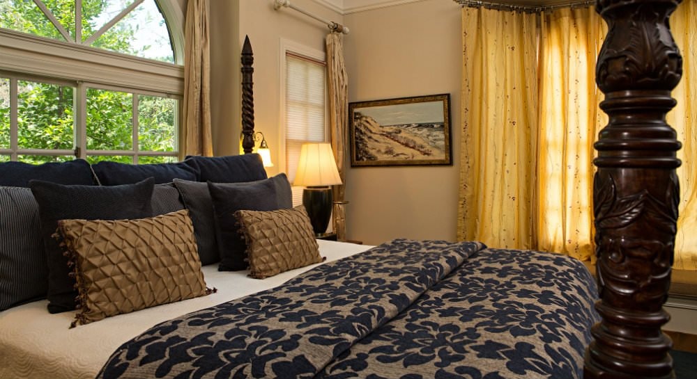 Cozy bedroom featuring a four-poster bed with decorative pillows and soft curtains.
