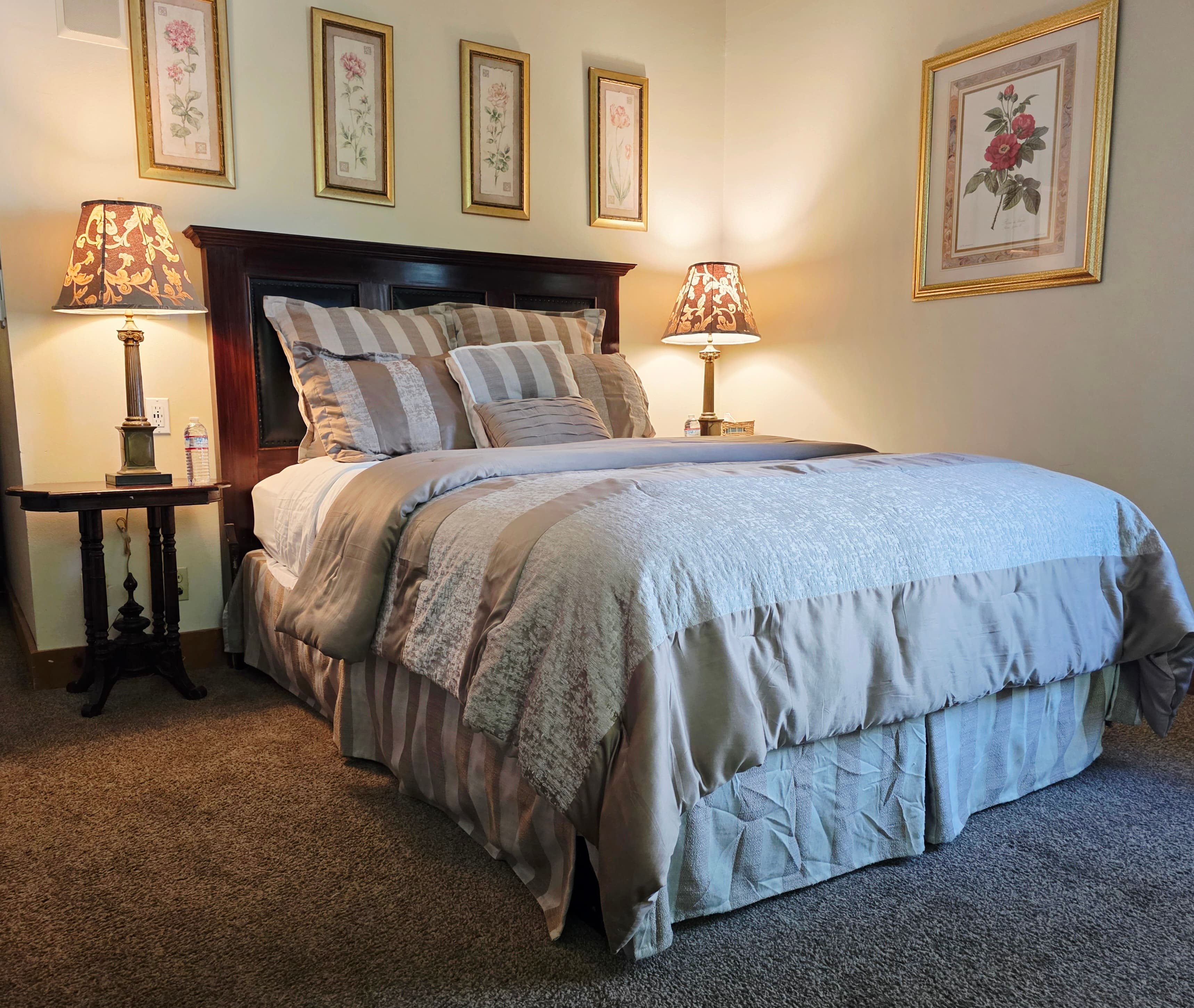 Cozy bedroom featuring a large bed, decorative pillows, and framed floral artwork on the walls.