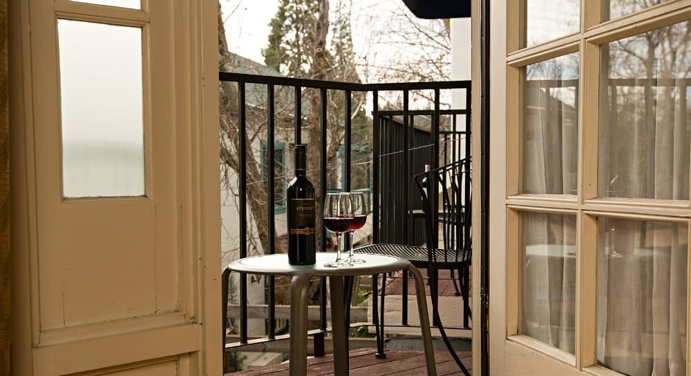 A balcony view featuring a bottle of wine and a glass on a small table.