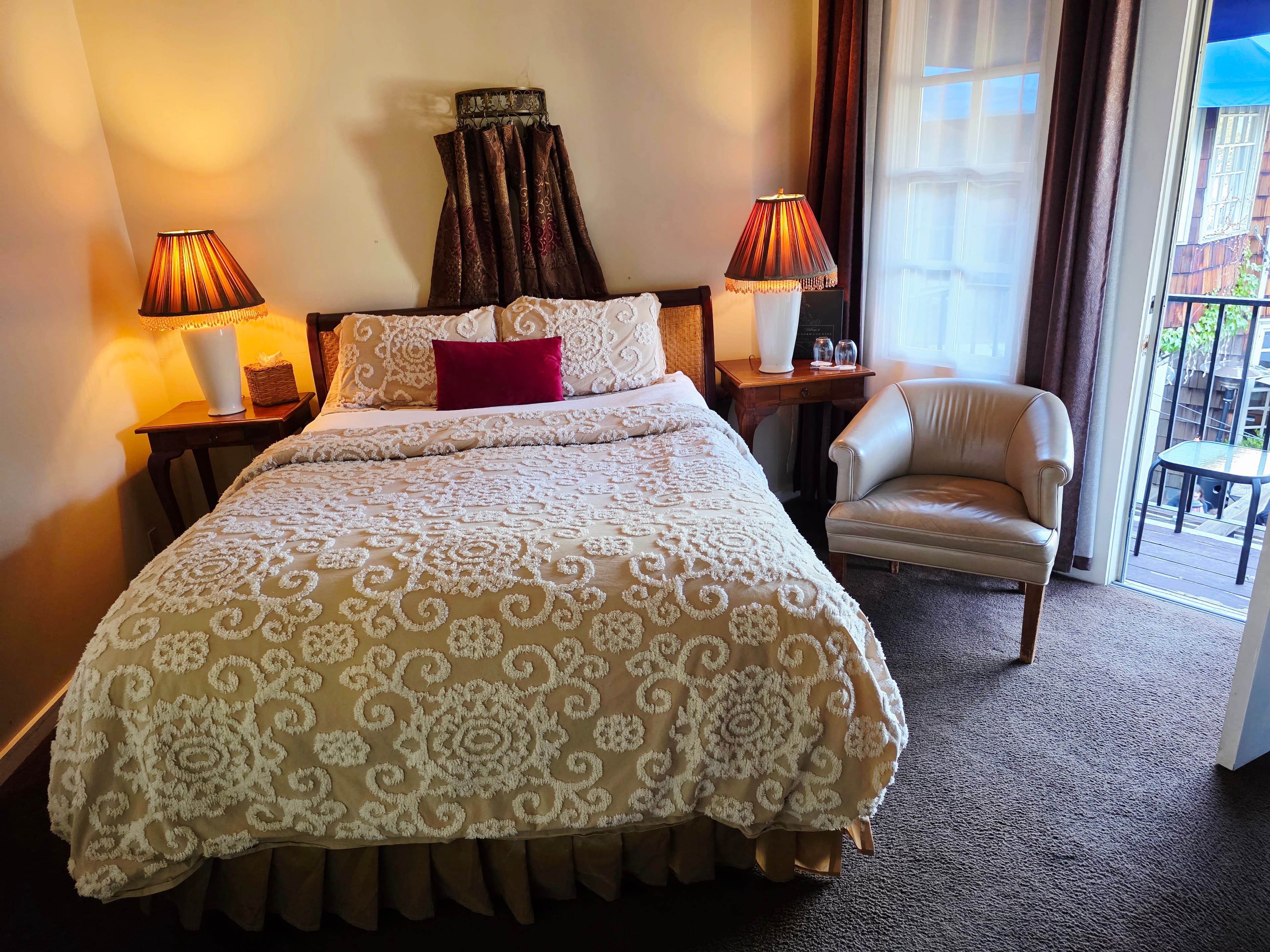 Cozy bedroom featuring a double bed, two lamps, and a seating area by a window.