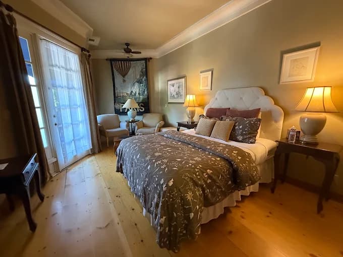 A cozy bedroom featuring a large bed, warm lighting, and seating by a window.
