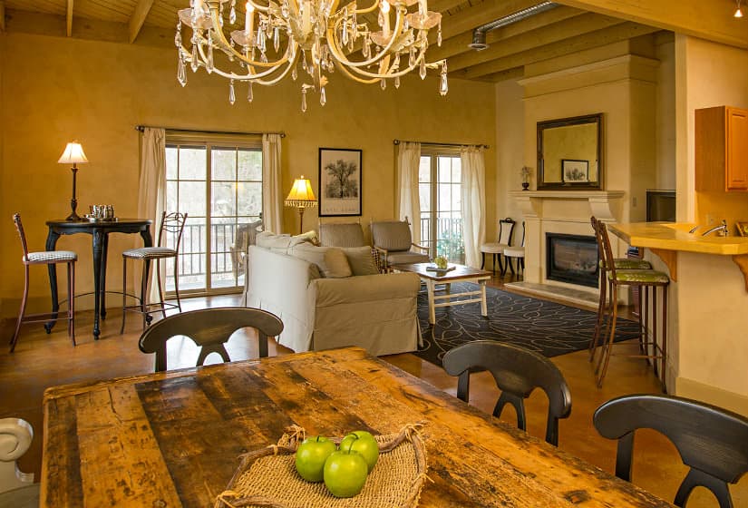 Cozy living area featuring a chandelier, comfortable seating, and a wooden dining table with green apples.