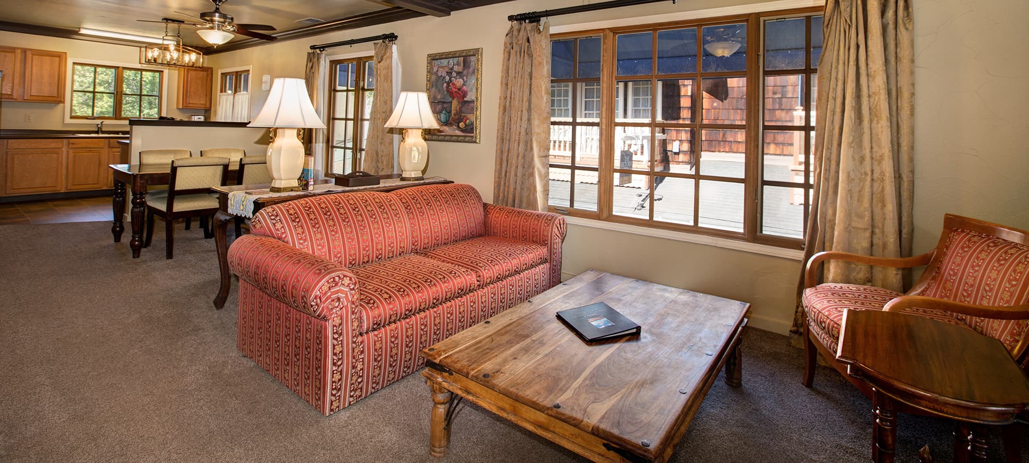 Cozy living room featuring a patterned sofa, wooden coffee table, and large windows.