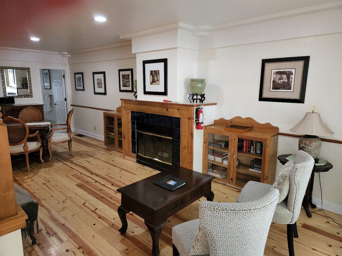 A cozy living room with wooden floors, a fireplace, and framed pictures on the walls.