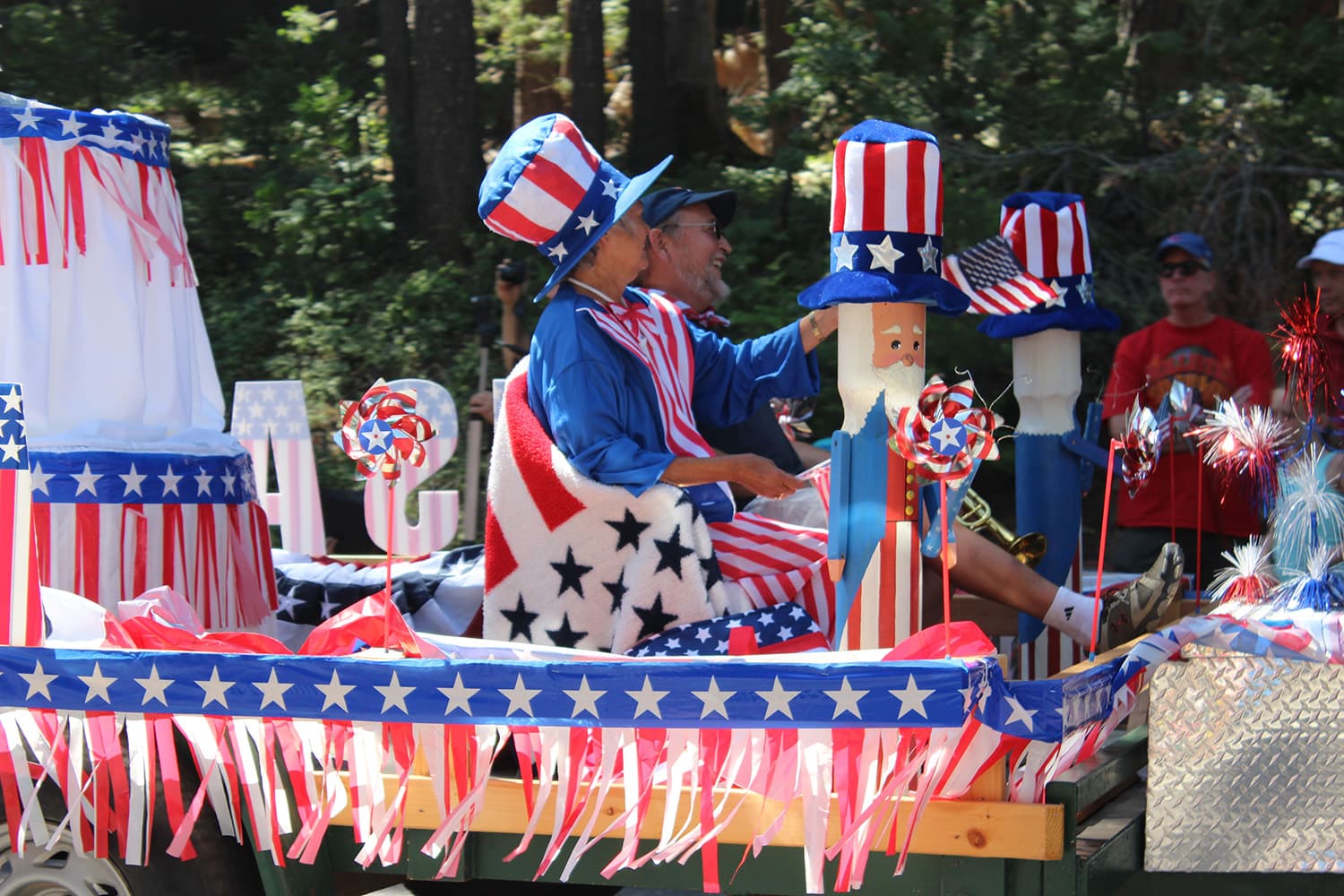 Patriotic Fourth of July parade float with red, white, and blue streamers, stars, an Uncle Sam figure, and people in festive hats. Patriotic Fourth of July parade float with red, white, and blue streamers, stars, an Uncle Sam figure, and people in festive hats.