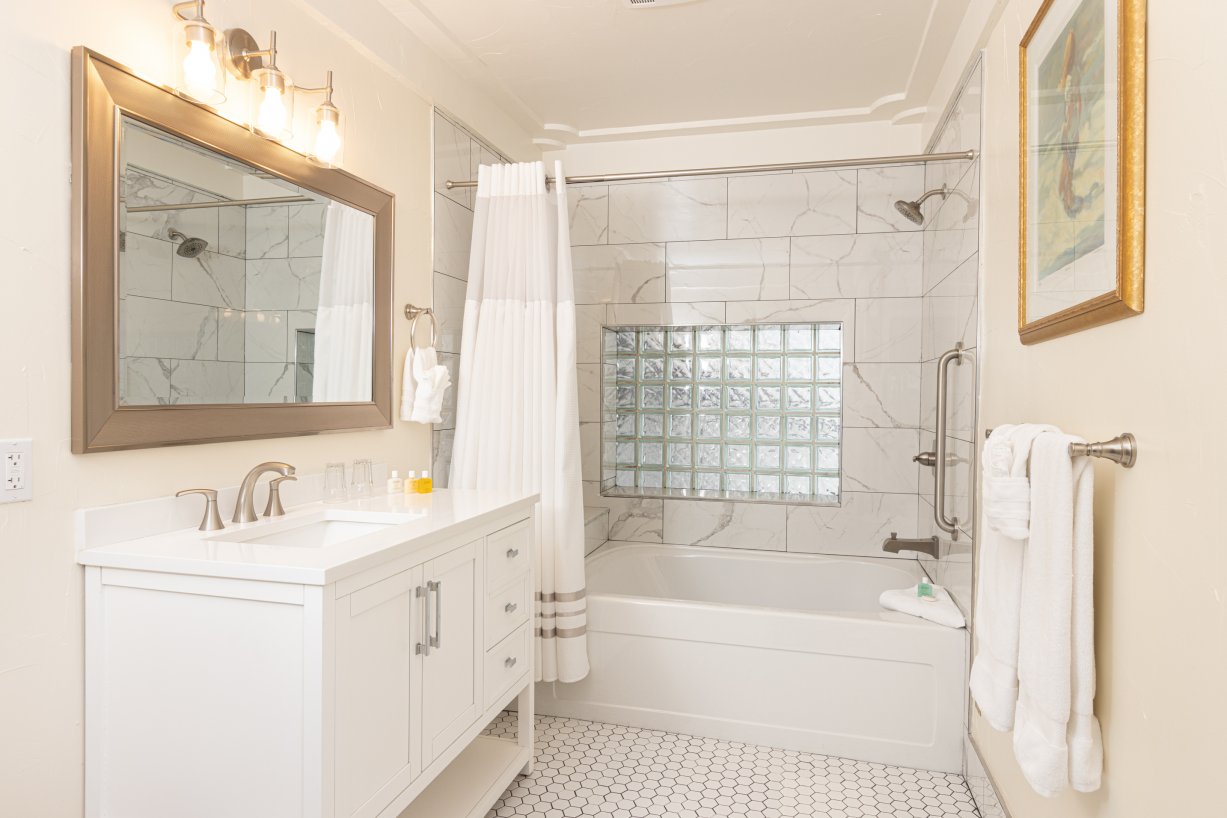 White marbled tiled tub, shower and sink with glass block privacy window, brush nickle fixtures and white towels