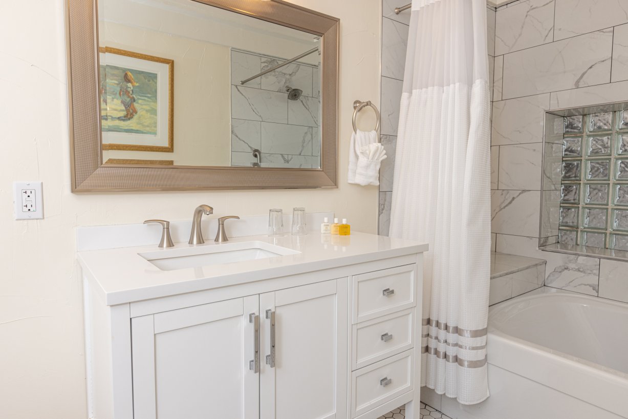 White marbled tiled tub, shower and sink with glass block privacy window, brush nickle fixtures and white towels
