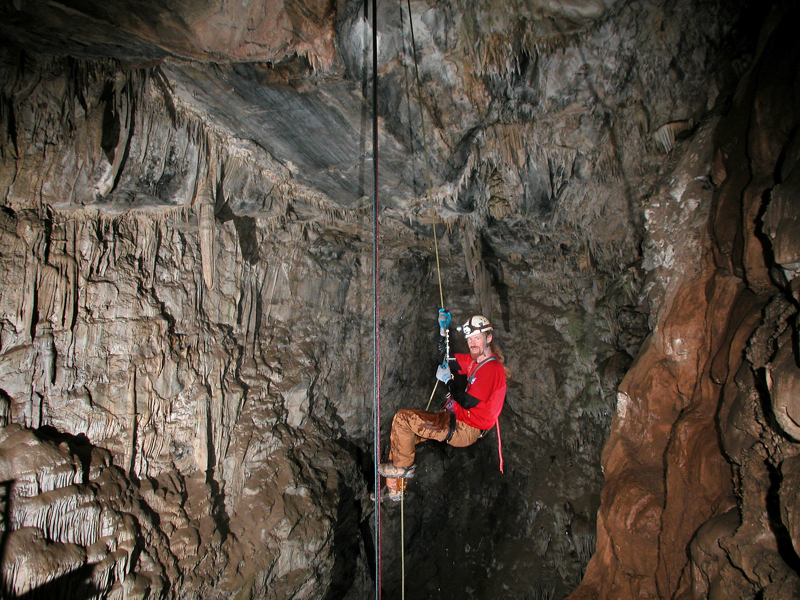 underground cavern in Calaveras County California man in red jumpsuit hard hat miner