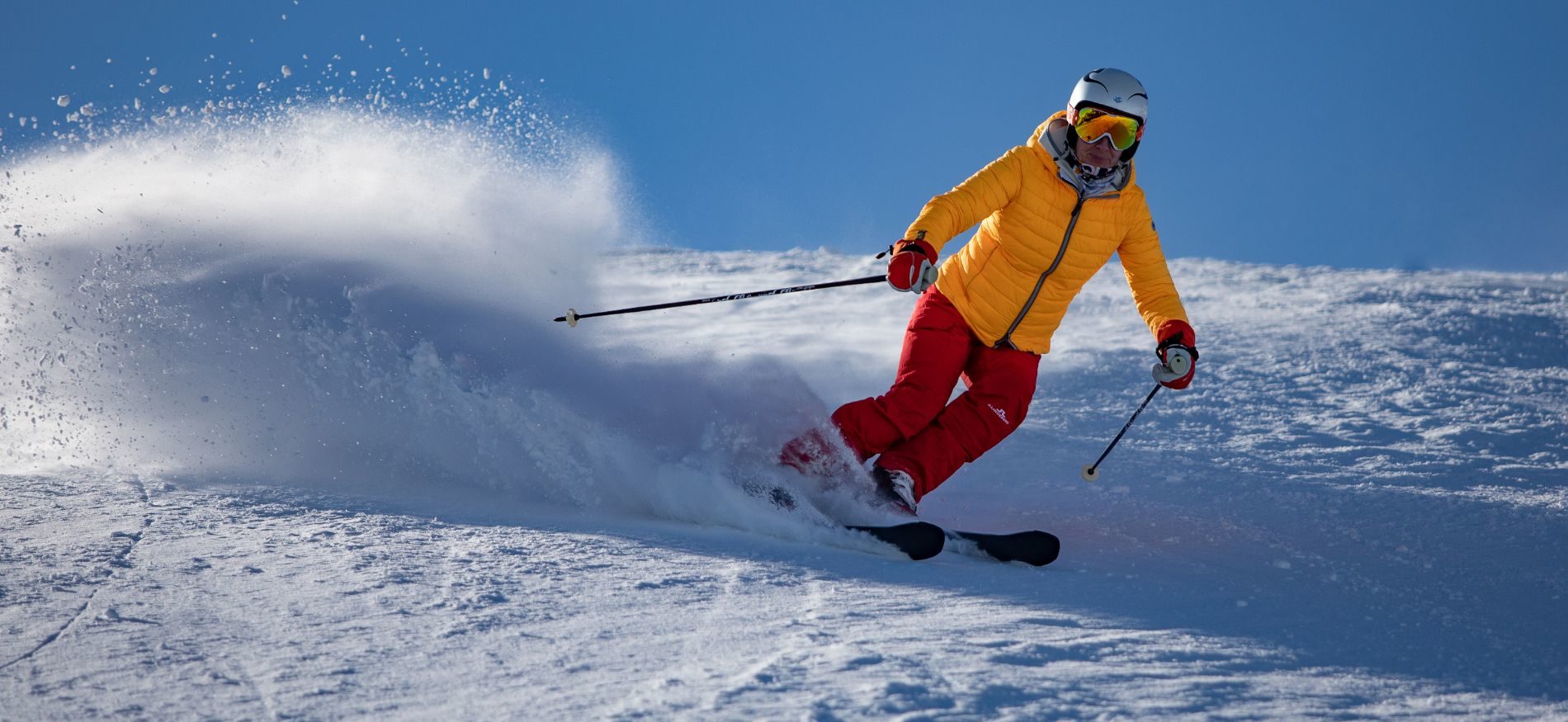 A person in a bright skiing outfit skiing down a mountain