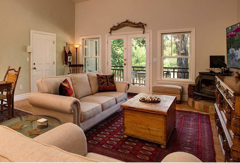 Living and dining areas with sofas separating spaces. Large bay windows in the background provide a view and natural lighting.