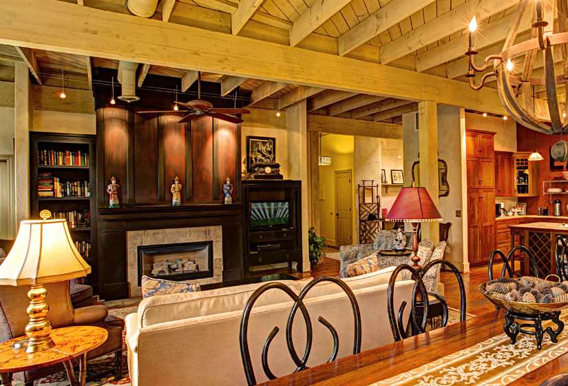 Living room with wood floors, and furniture and coffee table surrounding a warm fire in the fireplace