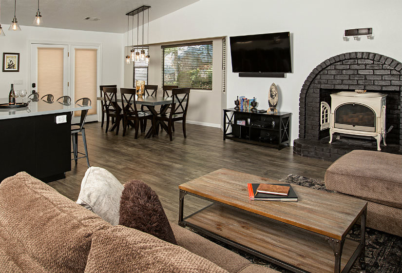 Large room with island seating, black dining table with six chairs, black brick arched fireplace, brown furniture and wood floors
